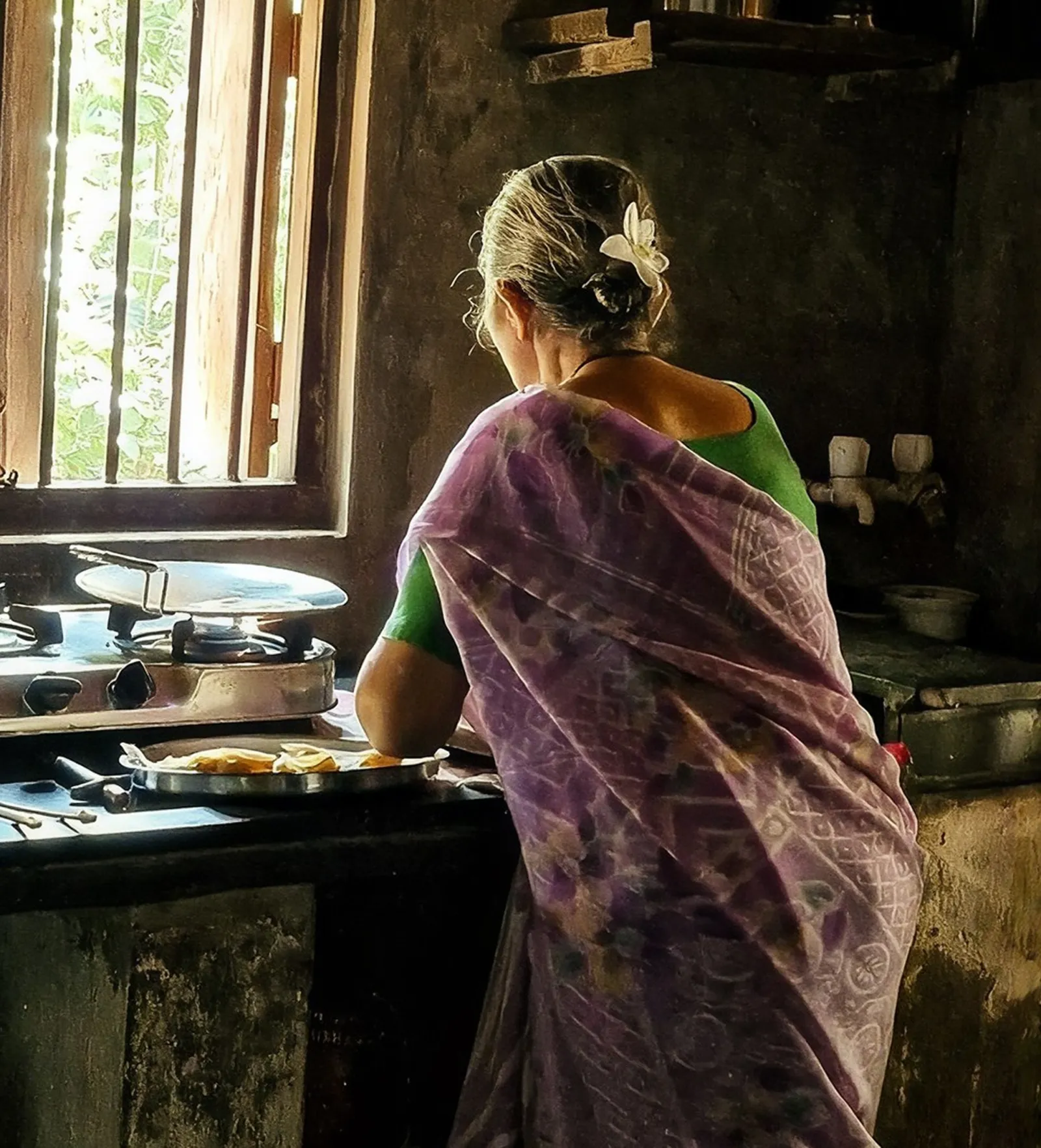 Woman in a sari cooking at a traditional home kitchen stove